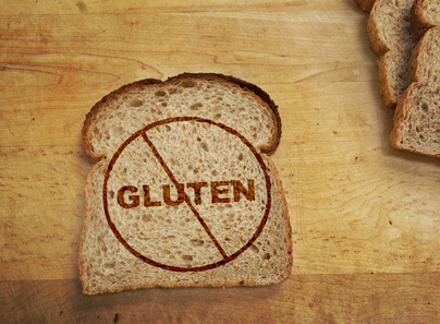 Slice of wheat bread with Gluten text crossed out -- Gluten free concept
